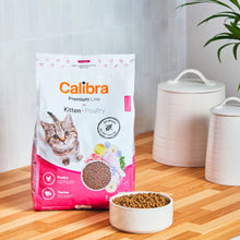 Saco de pienso Calibra Premium Line Kitten Poultry para gatitos junto a un cuenco de croquetas