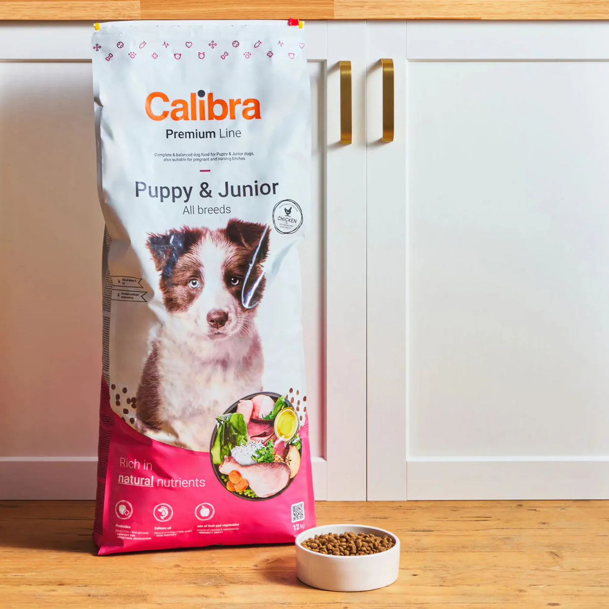 Saco de Calibra Premium Line Puppy & Junior junto a un cuenco de croquetas