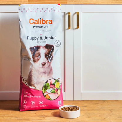 Saco de Calibra Premium Line Puppy & Junior junto a un cuenco de croquetas