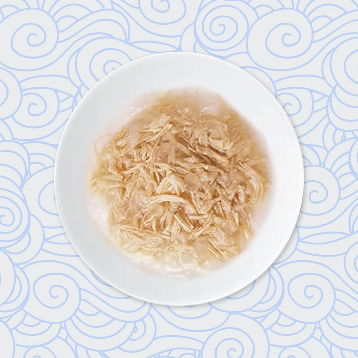 Plato blanco con tiras de pollo en un caldo claro, visto desde arriba sobre un fondo de olas azules