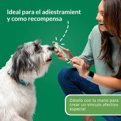 Mujer sentada ofreciendo un tubo a un perro gris y blanco, con un rótulo sobre adiestramiento y recompensa