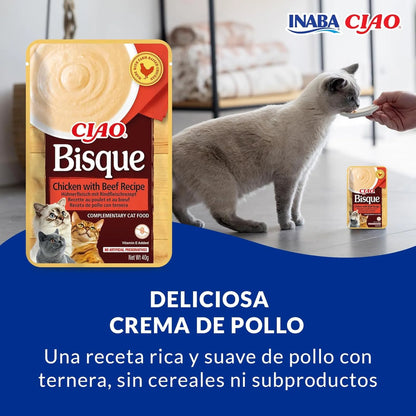 Gato gris tomando crema de la mano de una persona junto a la bolsa, con el rótulo «Deliciosa crema de pollo»
