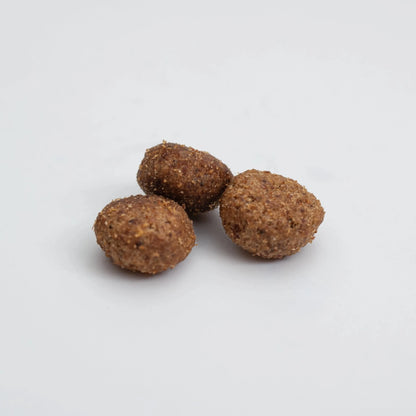 Primer plano de tres croquetas del pienso HPM Hypoallergy A2 para gatos, textura rugosa y forma oval