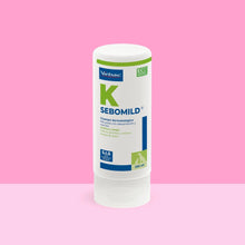 Bote Sebomild K Virbac champú dermatológico 250 ml sobre fondo rosa vibrante, etiqueta blanca y azul con letra K verde, texto Piel grasa con descamación y mal olor, purifica y limpia, elimina escamas costras y exceso de grasa, sellos SIS y ECO FRIENDLY PACKAGING