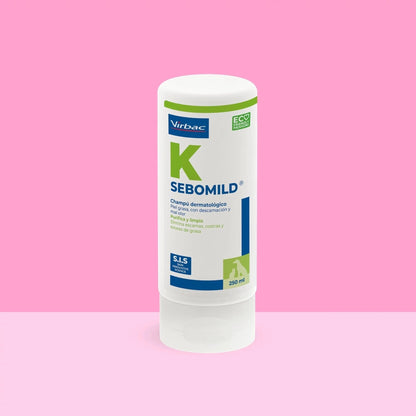 Bote Sebomild K Virbac champú dermatológico 250 ml sobre fondo rosa vibrante, etiqueta blanca y azul con letra K verde, texto Piel grasa con descamación y mal olor, purifica y limpia, elimina escamas costras y exceso de grasa, sellos SIS y ECO FRIENDLY PACKAGING