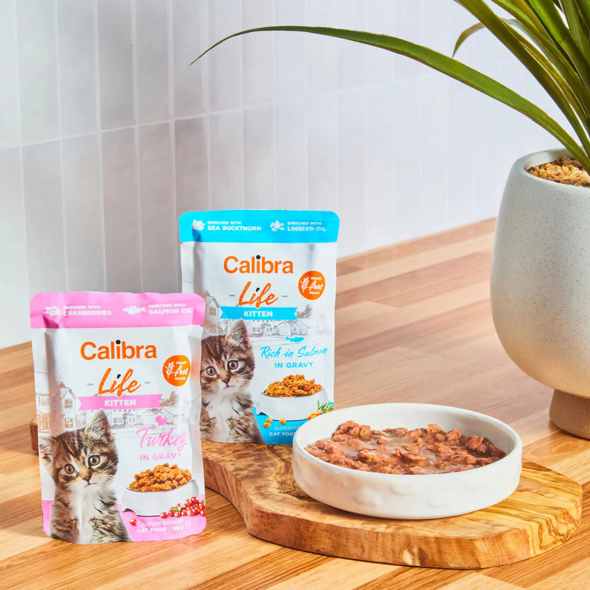 Sobres Calibra Life Kitten de pavo y salmón junto a un cuenco servido